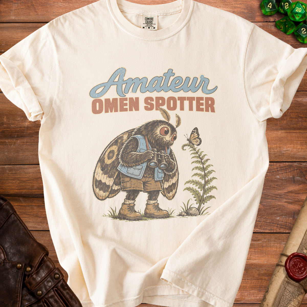 Cream t-shirt with "Amateur Omen Spotter" text and a moth holding binoculars.