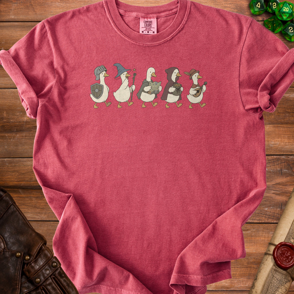 Five cartoon ducks in fantasy adventuring attire march across a pink t-shirt.