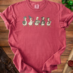 Five cartoon ducks in fantasy adventuring attire march across a pink t-shirt.
