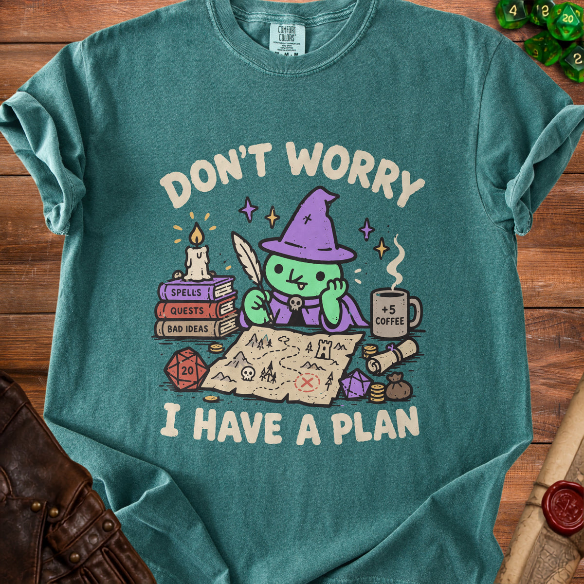 Green t-shirt with a cartoon witch planning a quest on a treasure map.