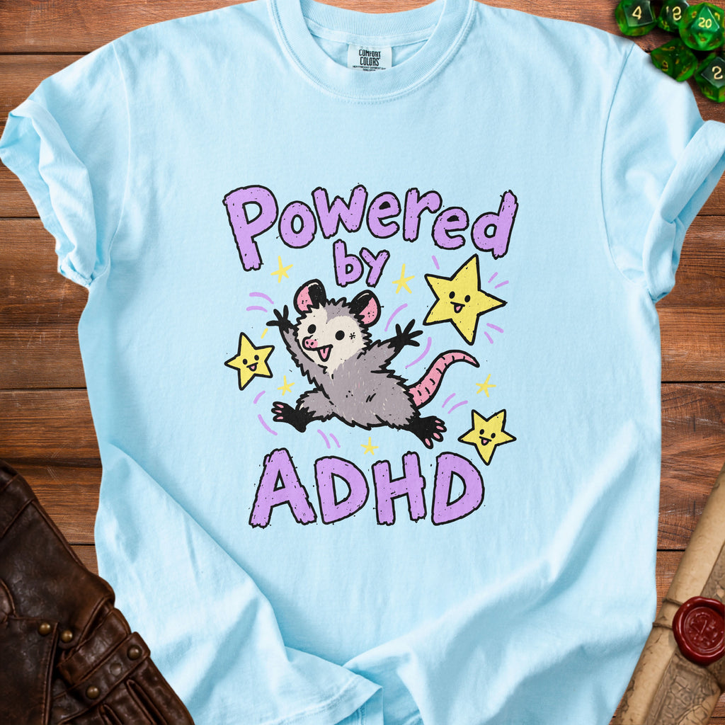 Light blue t-shirt with cartoon possum and text "Powered by ADHD".