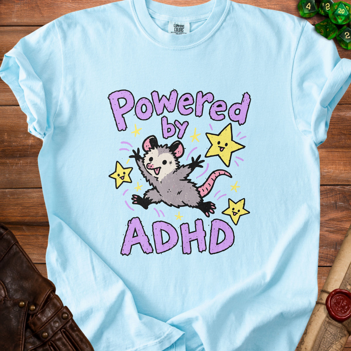 Light blue t-shirt with cartoon possum and text "Powered by ADHD".