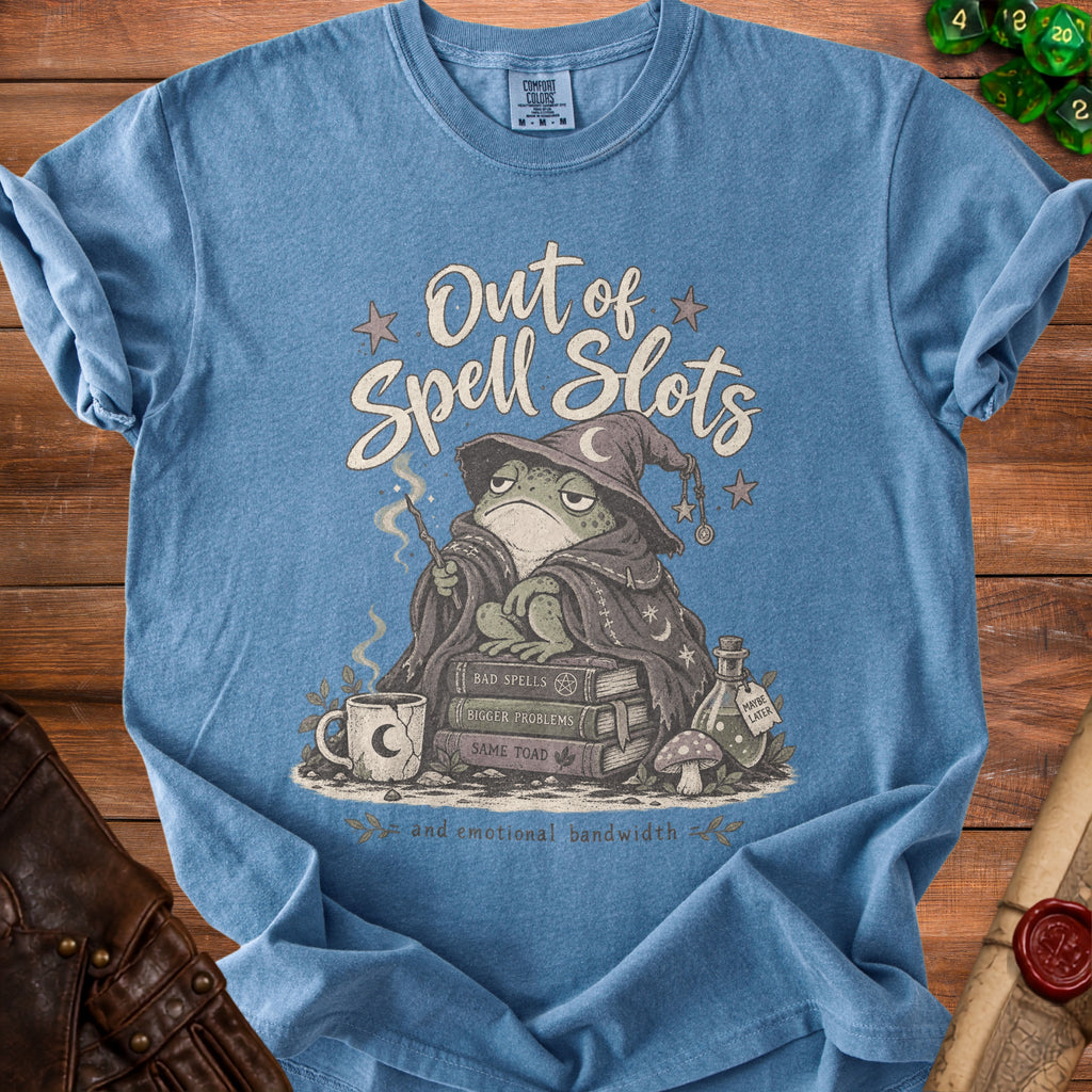 Blue t-shirt with a wizard frog illustration, text "Out of Spell Slots", and "and emotional bandwidth".