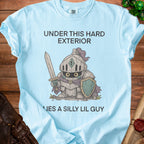 Light blue t-shirt with text "UNDER THIS HARD EXTERIOR LIES A SILLY LIL GUY" and knight graphic.