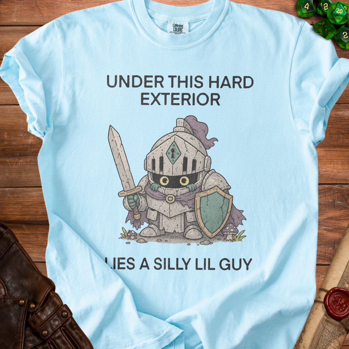 Light blue t-shirt with text "UNDER THIS HARD EXTERIOR LIES A SILLY LIL GUY" and knight graphic.