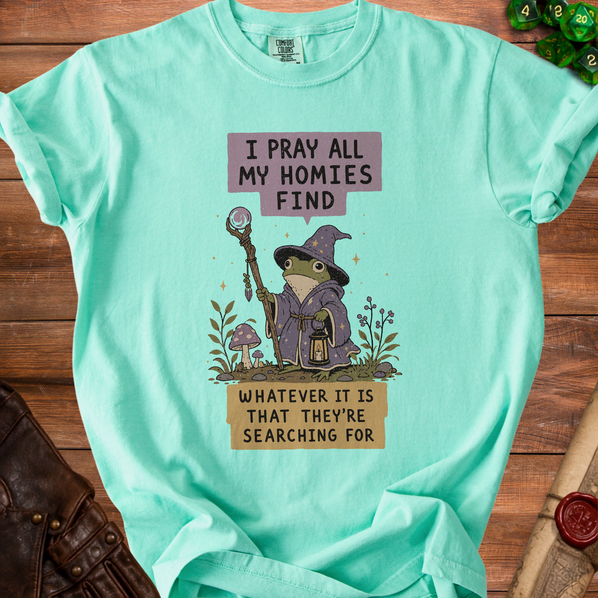 Teal t-shirt with frog wizard graphic and text "I pray all my homies find whatever it is that they're searching for."