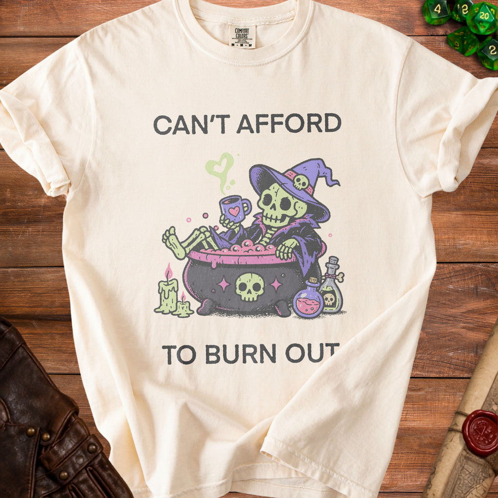 Cream t-shirt with skeleton in cauldron graphic and text "CAN'T AFFORD TO BURN OUT".