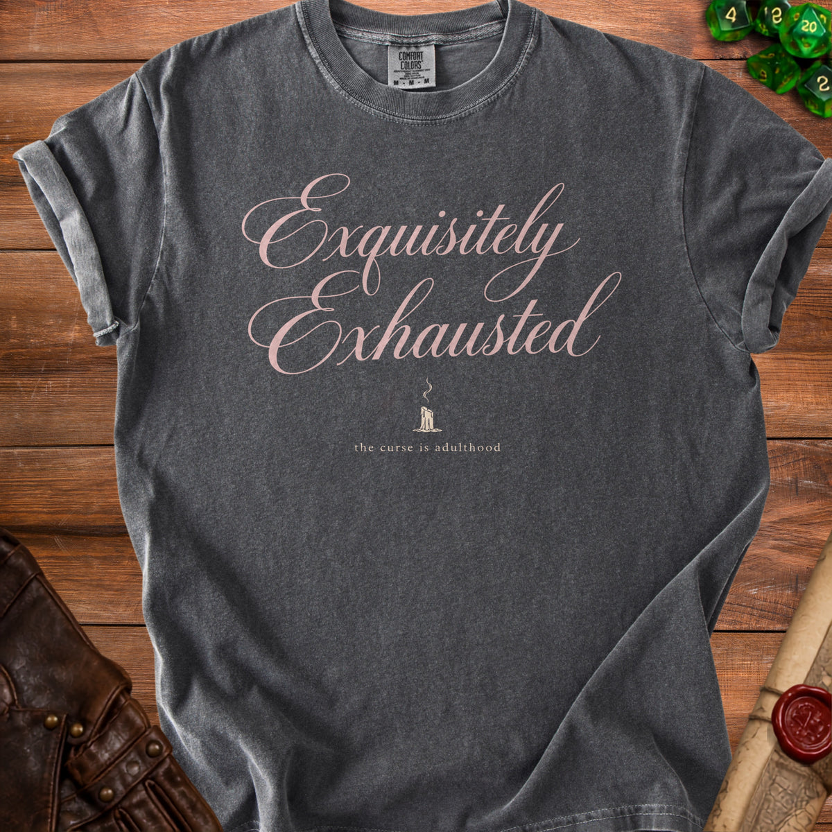Dark gray t-shirt with pink text reading "Exquisitely Exhausted" and "the curse is adulthood".