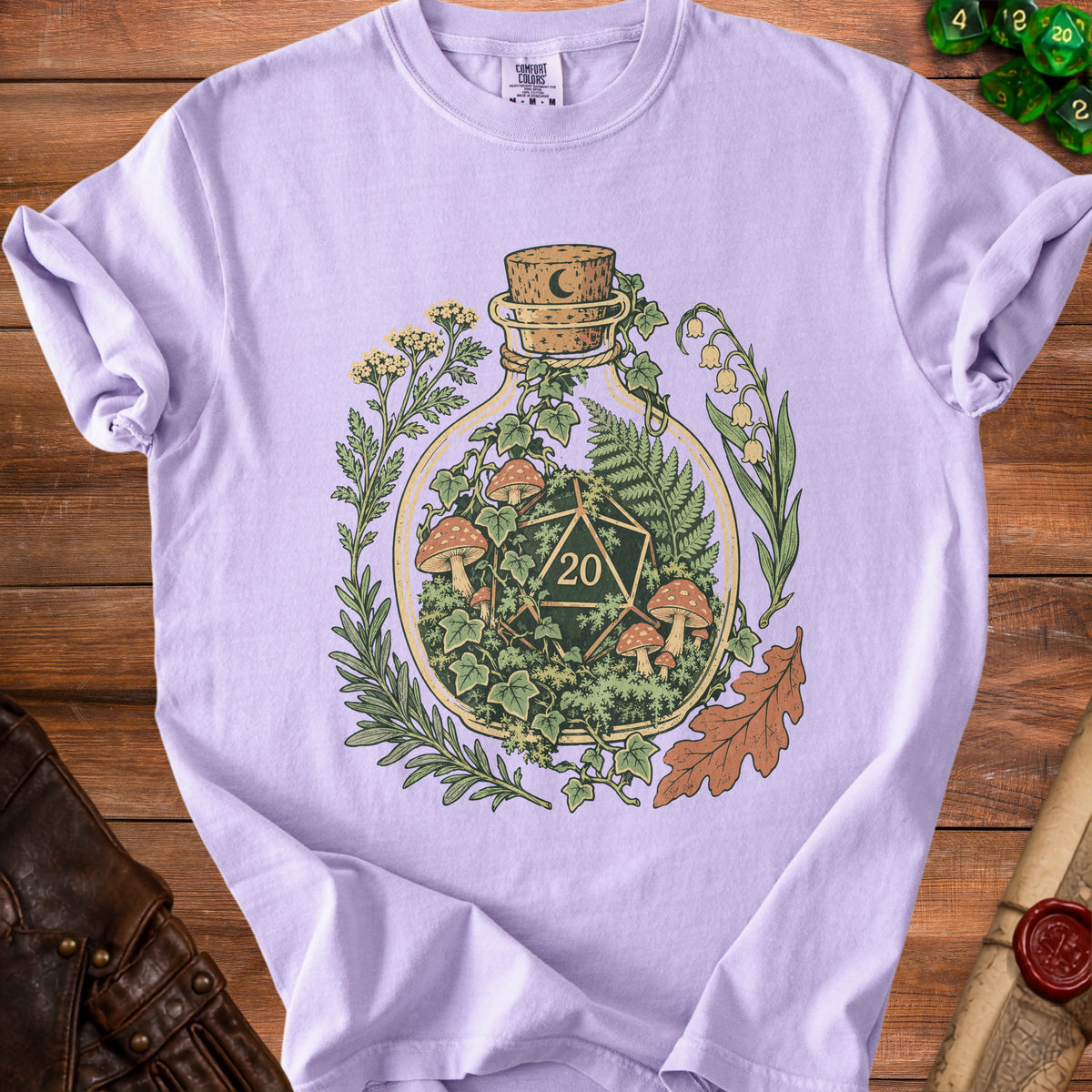 Light purple t-shirt with a glass bottle containing a d20 die, mushrooms, and plants.