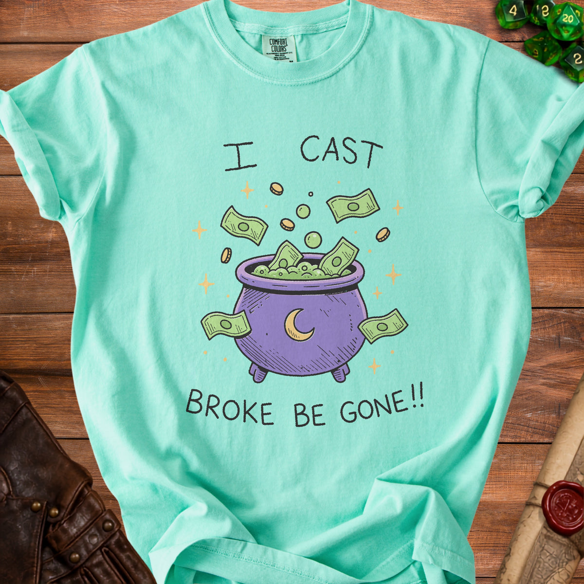 Mint t-shirt with illustration of cauldron overflowing with money and text "I CAST BROKE BE GONE!!".