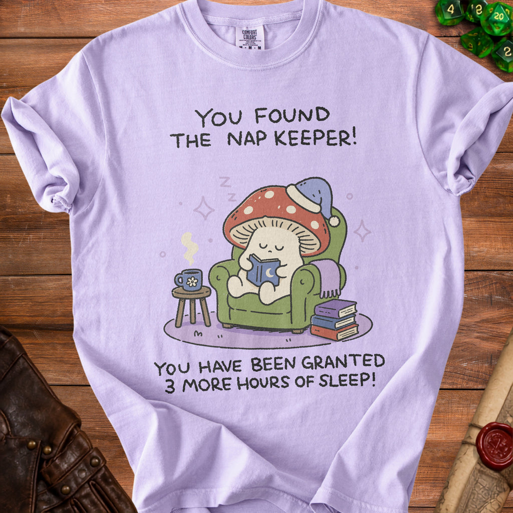 T-shirt with a mushroom character reading a book that says, "You found the nap keeper! You have been granted 3 more hours of sleep!"