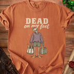 T-shirt with a skeleton graphic holding grocery bags and text "DEAD on my feet".