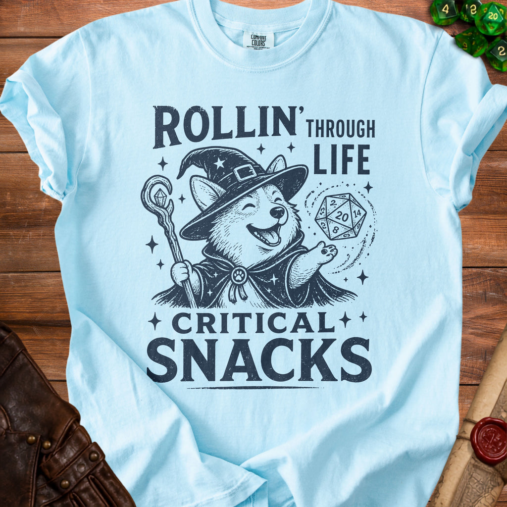 Corgi wizard with dice and staff on light blue t-shirt, text reads "Rollin' Through Life Critical Snacks".