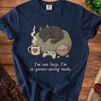 Navy t-shirt with a black cat sleeping on a pillow, game controller, popcorn, and coffee.