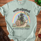 Light green t-shirt with black cat riding a snail under a rainbow.