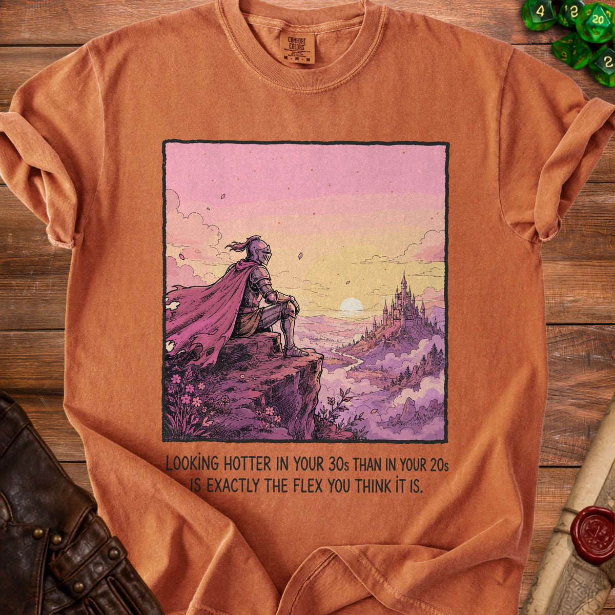 Orange t-shirt with knight overlooking castle and text "Looking hotter in your 30s than in your 20s is exactly the flex you think it is."