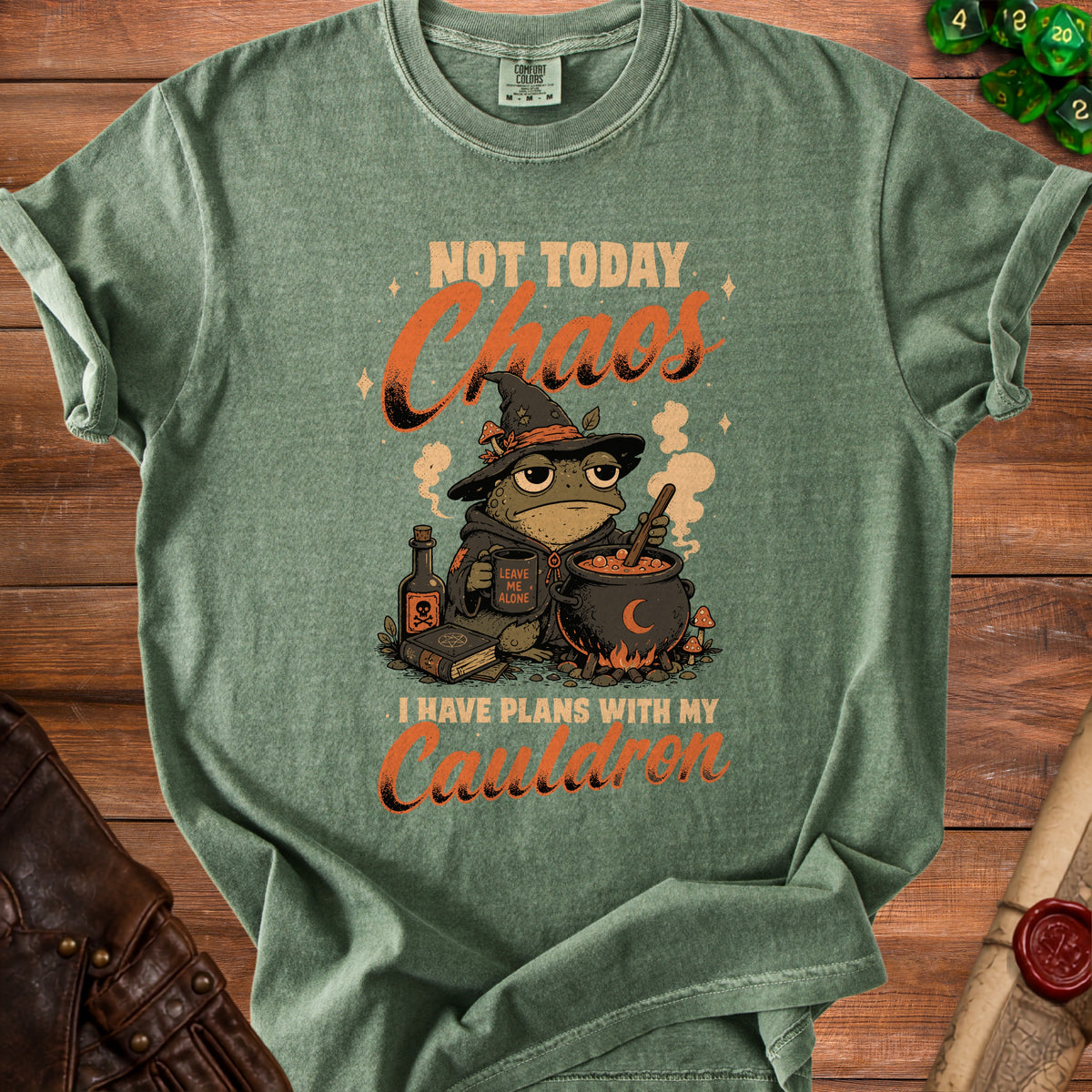 Green t-shirt with illustration of a frog in a witch hat, text "Not Today Chaos" and "I Have Plans With My Cauldron".