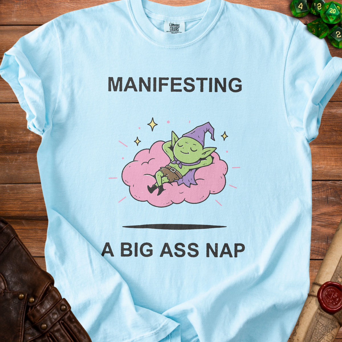 Light blue t-shirt with "MANIFESTING A BIG ASS NAP" and a goblin on a cloud graphic.