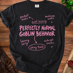 Black t-shirt with pink text "PERFECTLY NORMAL GOBLIN BEHAVIOR" and related phrases.