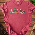 Duck characters in adventuring clothes sit around a campfire on a red t-shirt.