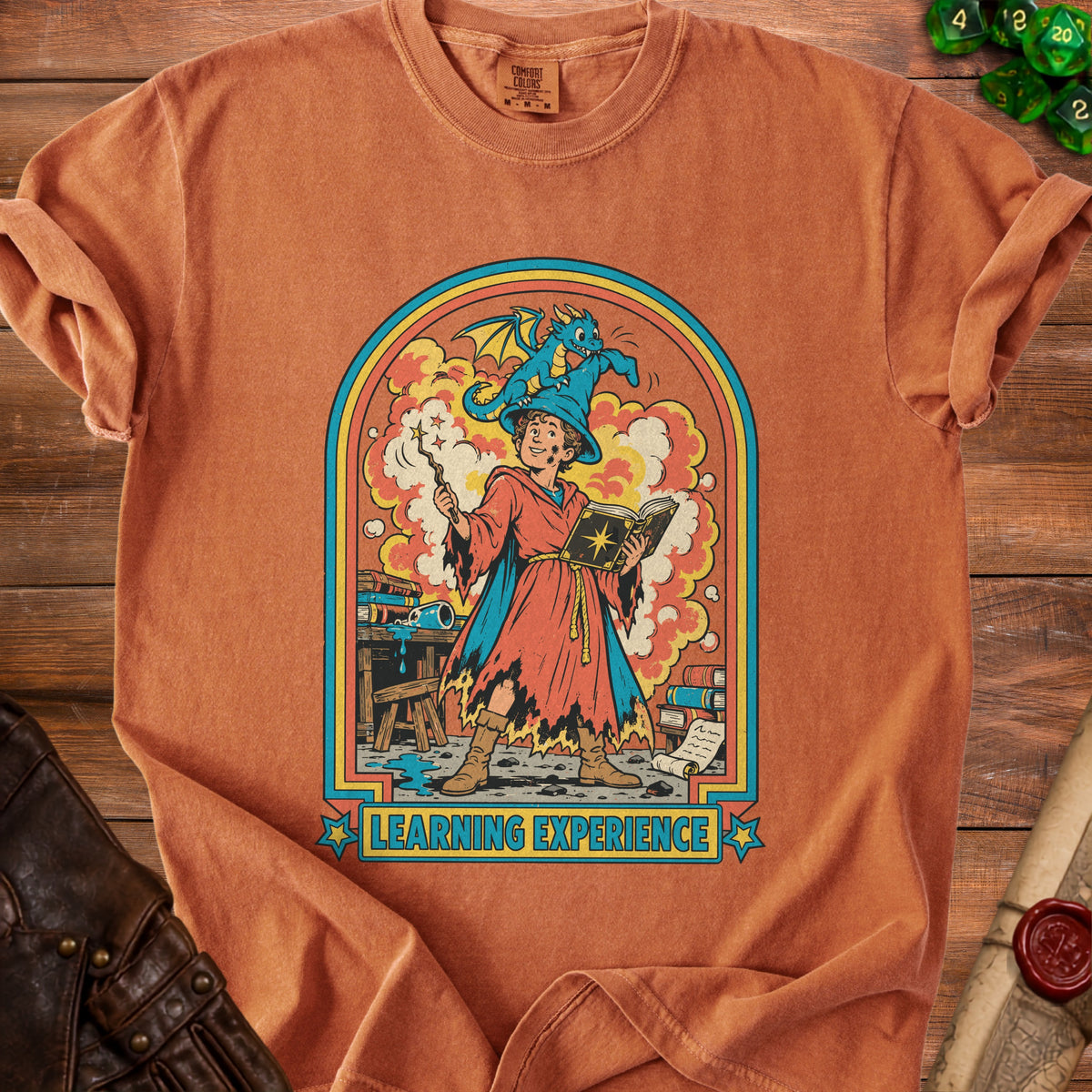 Orange t-shirt featuring a wizard with a dragon on his hat, reading a book.