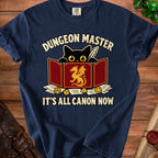 Navy t-shirt with black cat, dragon shield, dice, and text: Dungeon Master, It's All Canon Now.