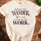 Cream t-shirt with "Born to Wander. Cursed to Work." text and graphics.
