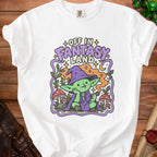 White t-shirt with graphic of a green goblin in a wizard hat reading "Off in Fantasy Land".