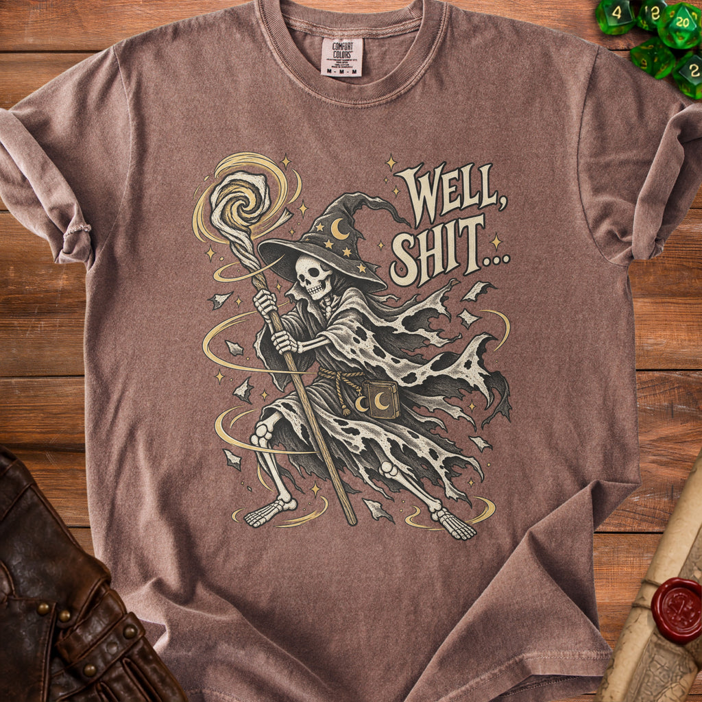Skeleton wizard graphic with text "WELL, SHIT..." on a brown t-shirt.