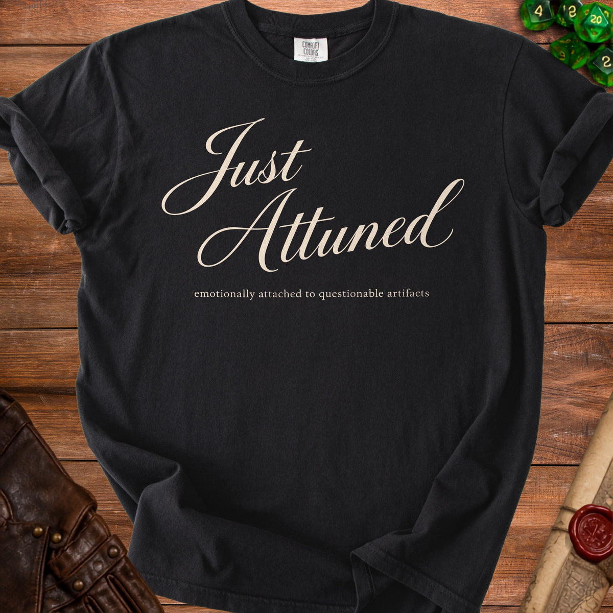 A black t-shirt printed with the beige text Just Attuned and emotionally attached to questionable artifacts.