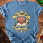 Blue t-shirt with dice, book, quill, and text "LORE MANAGEMENT IT WAS IN MY NOTES".
