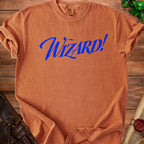 Orange Comfort Colors t-shirt with blue "Wizard!" text, on wooden background with dice.