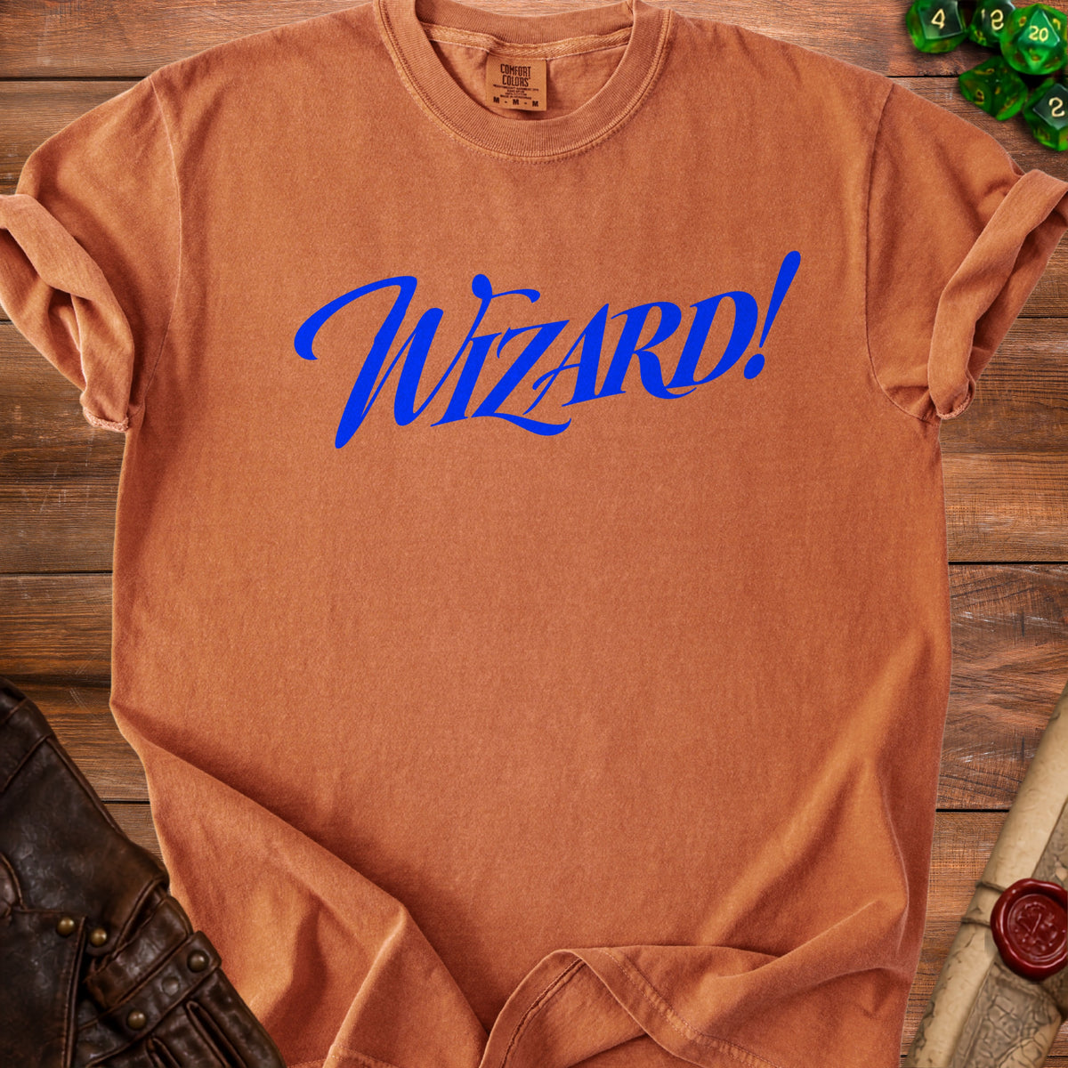 Orange Comfort Colors t-shirt with blue "Wizard!" text, on wooden background with dice.