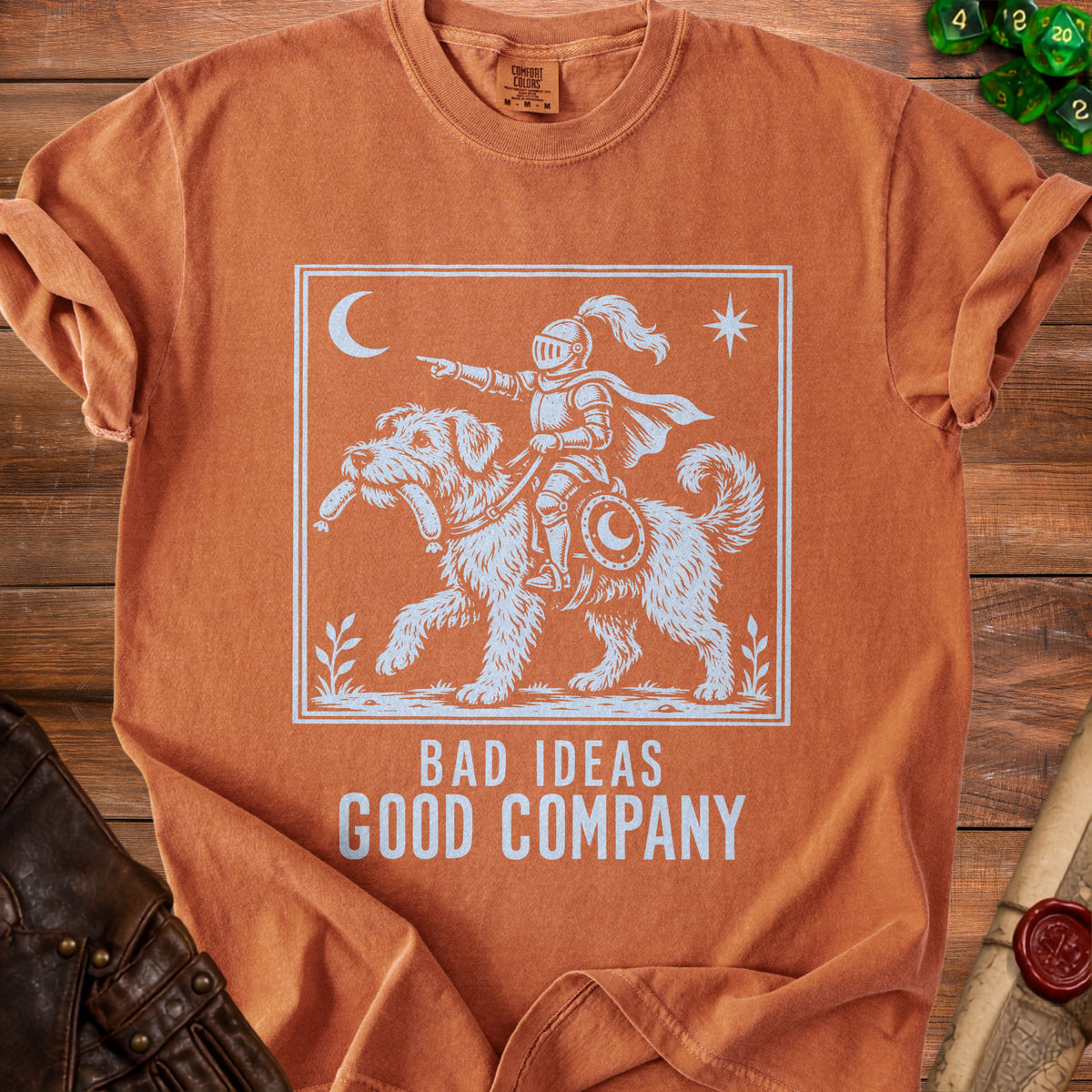 Orange t-shirt with knight on dog graphic and text "BAD IDEAS GOOD COMPANY".