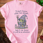 Pink t-shirt with frog wizard illustration and text: "I don't know what lies ahead... but I do know it will be an adventure."