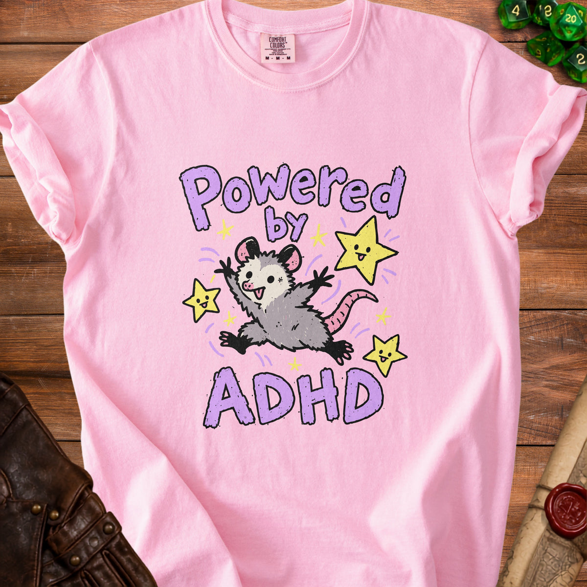 Pink t-shirt with "Powered by ADHD" text and a cartoon opossum.
