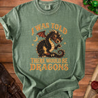 Green t-shirt with a vintage black dragon design and text that says "I WAS TOLD THERE WOULD BE DRAGONS".