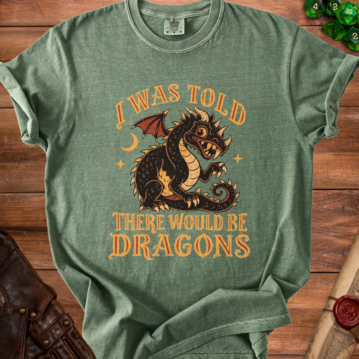 Green t-shirt with a vintage black dragon design and text that says "I WAS TOLD THERE WOULD BE DRAGONS".