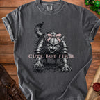 T-shirt with a detailed drawing of a cat in armor wearing a pink bow, text says "CUTE BUT FERAL."