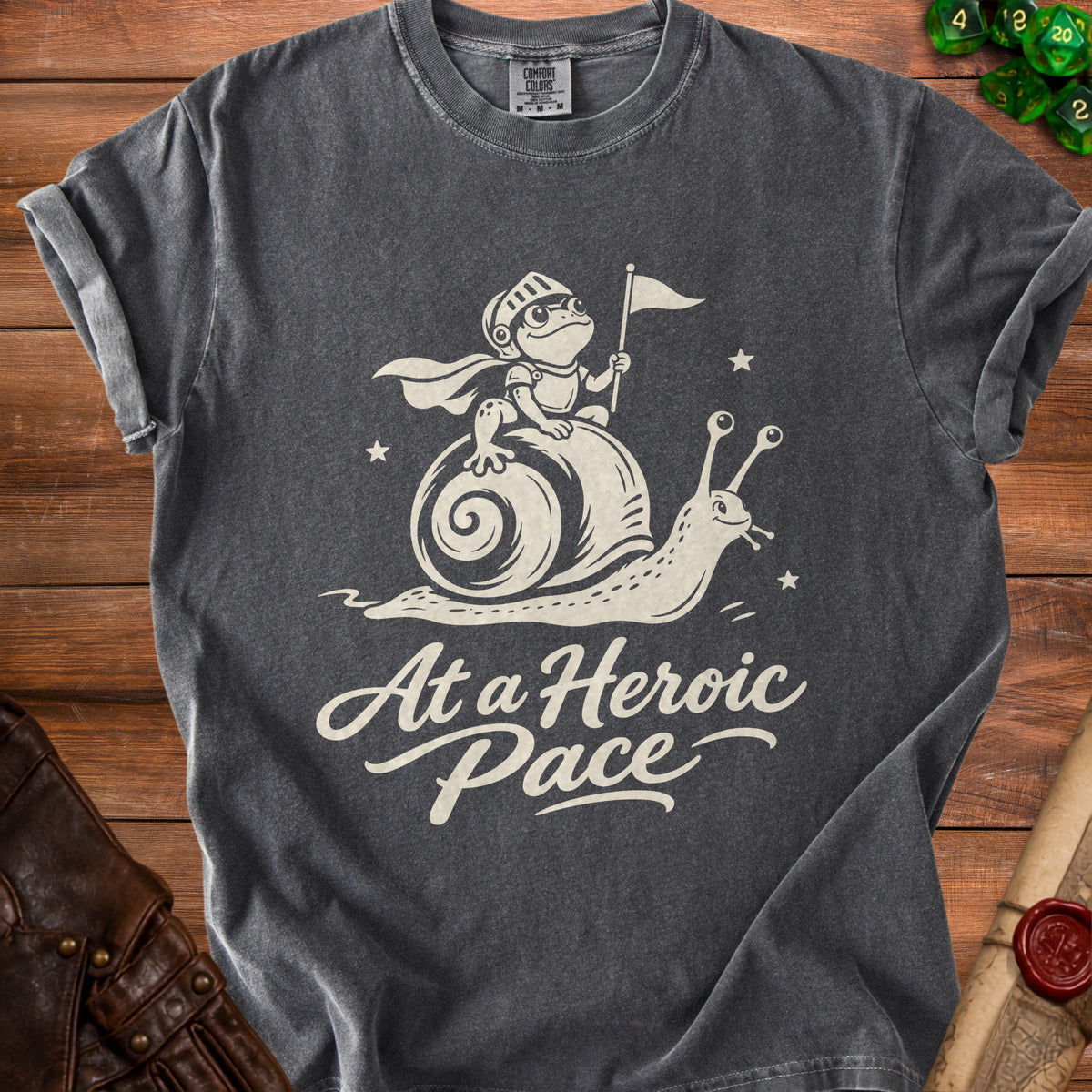 Dark grey t-shirt with a knight frog on a snail and the text "At a Heroic Pace".