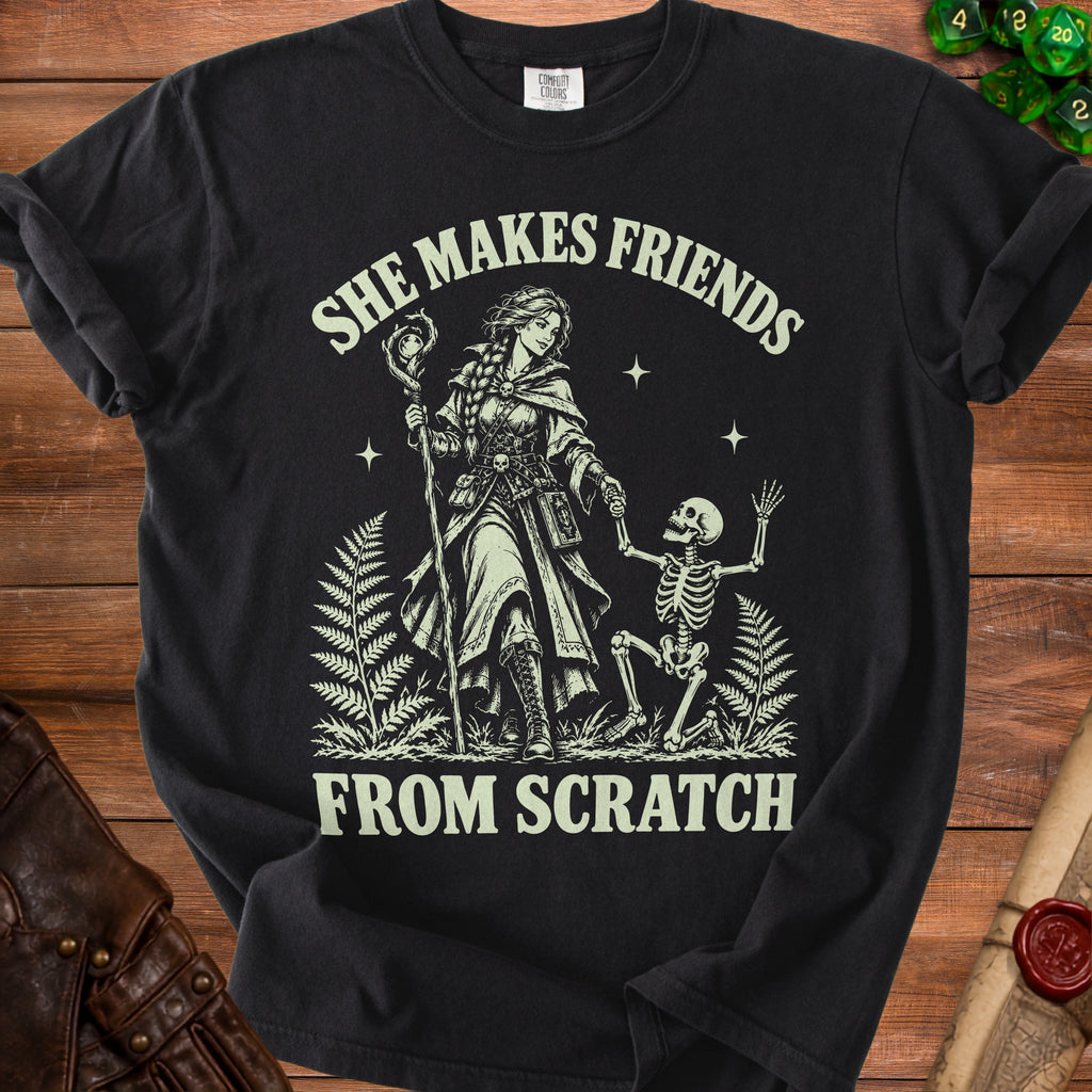 Black t-shirt with "She Makes Friends From Scratch" text and fantasy illustration.