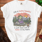 White t-shirt with graphic of crowned goblin holding coffee, "Life is lowkey beautiful" and "I just have a lot of hate in my heart".