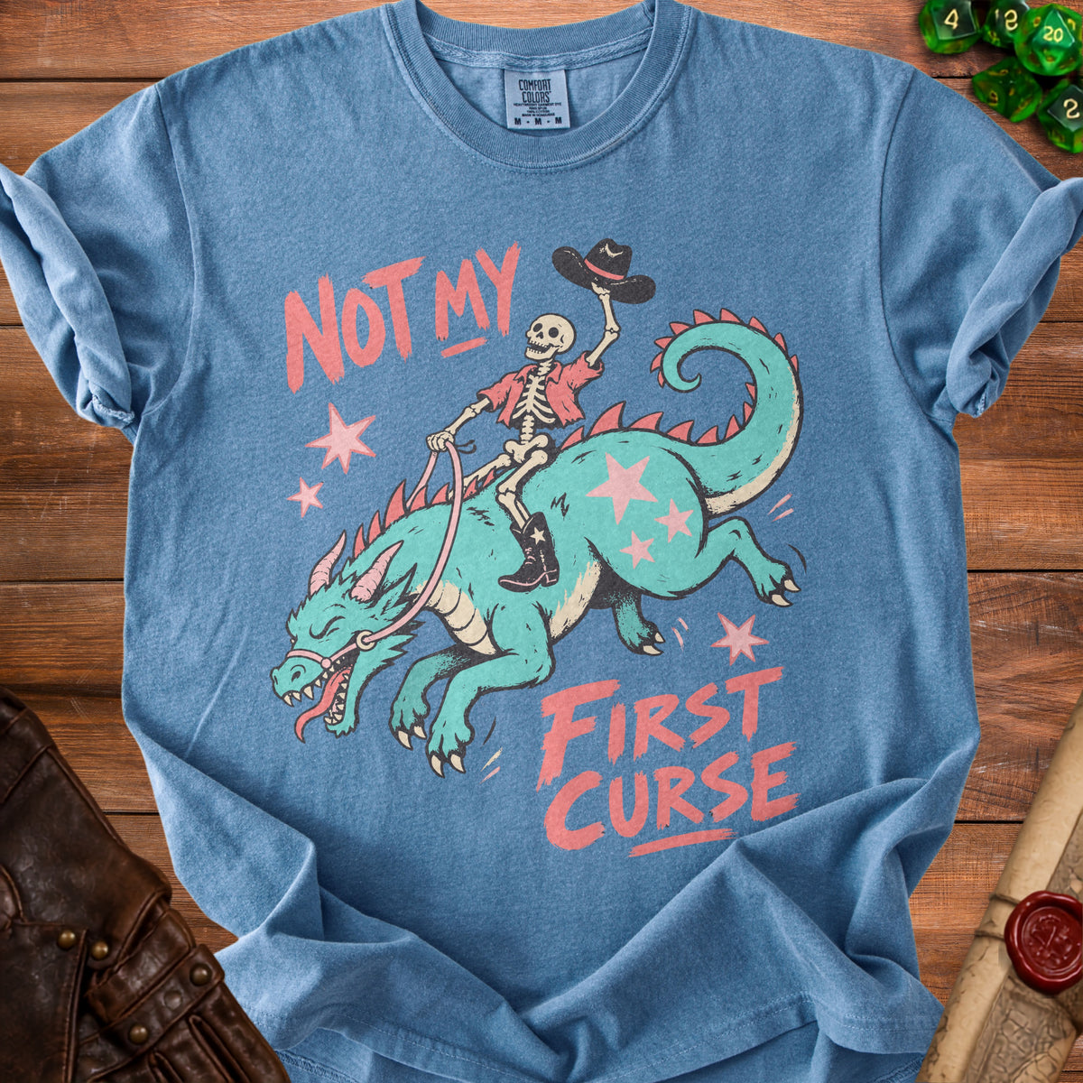 Skeleton riding a dragon graphic with text "NOT MY FIRST CURSE" on blue shirt.