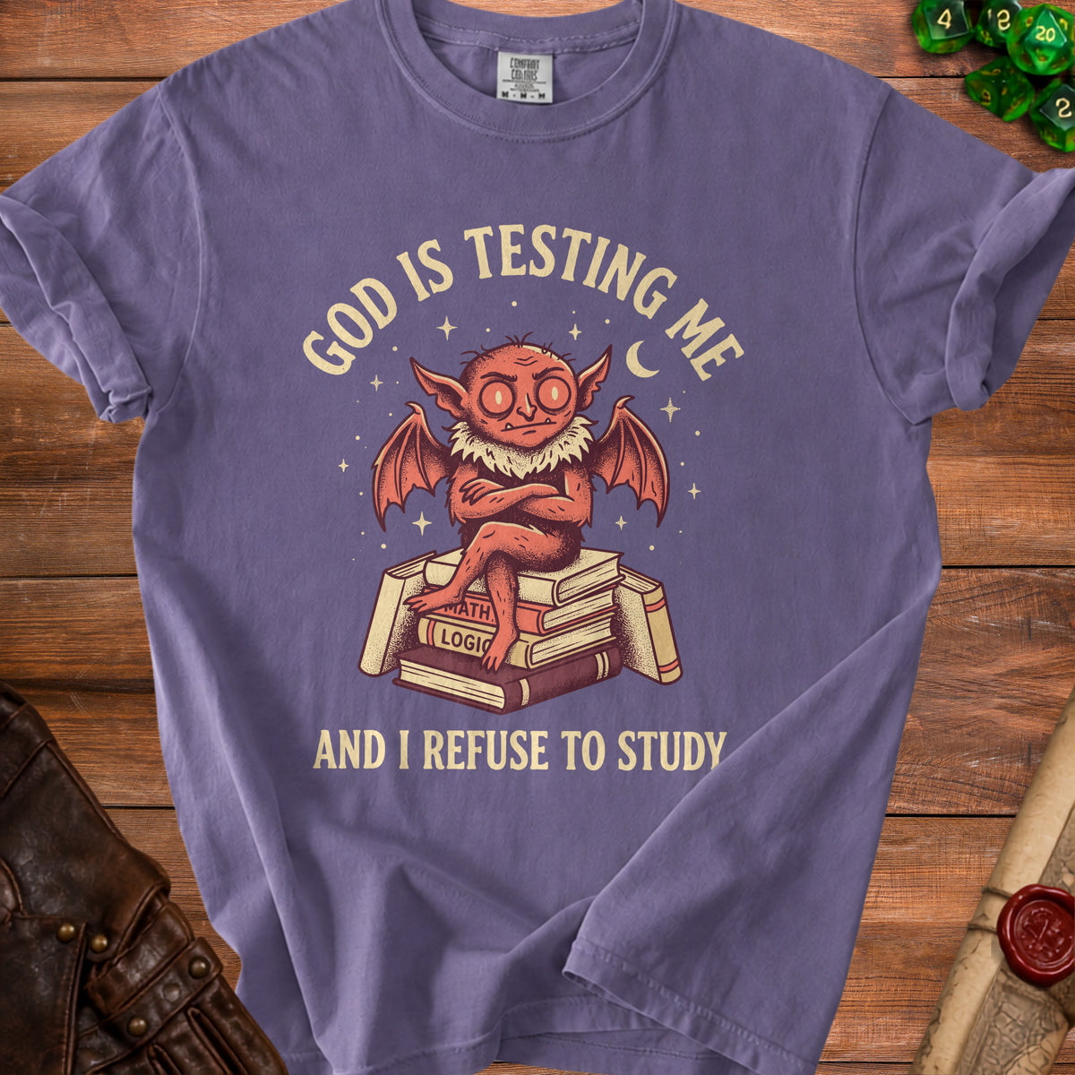 Purple t-shirt with a graphic of a devil sitting on books saying "God is testing me and I refuse to study."