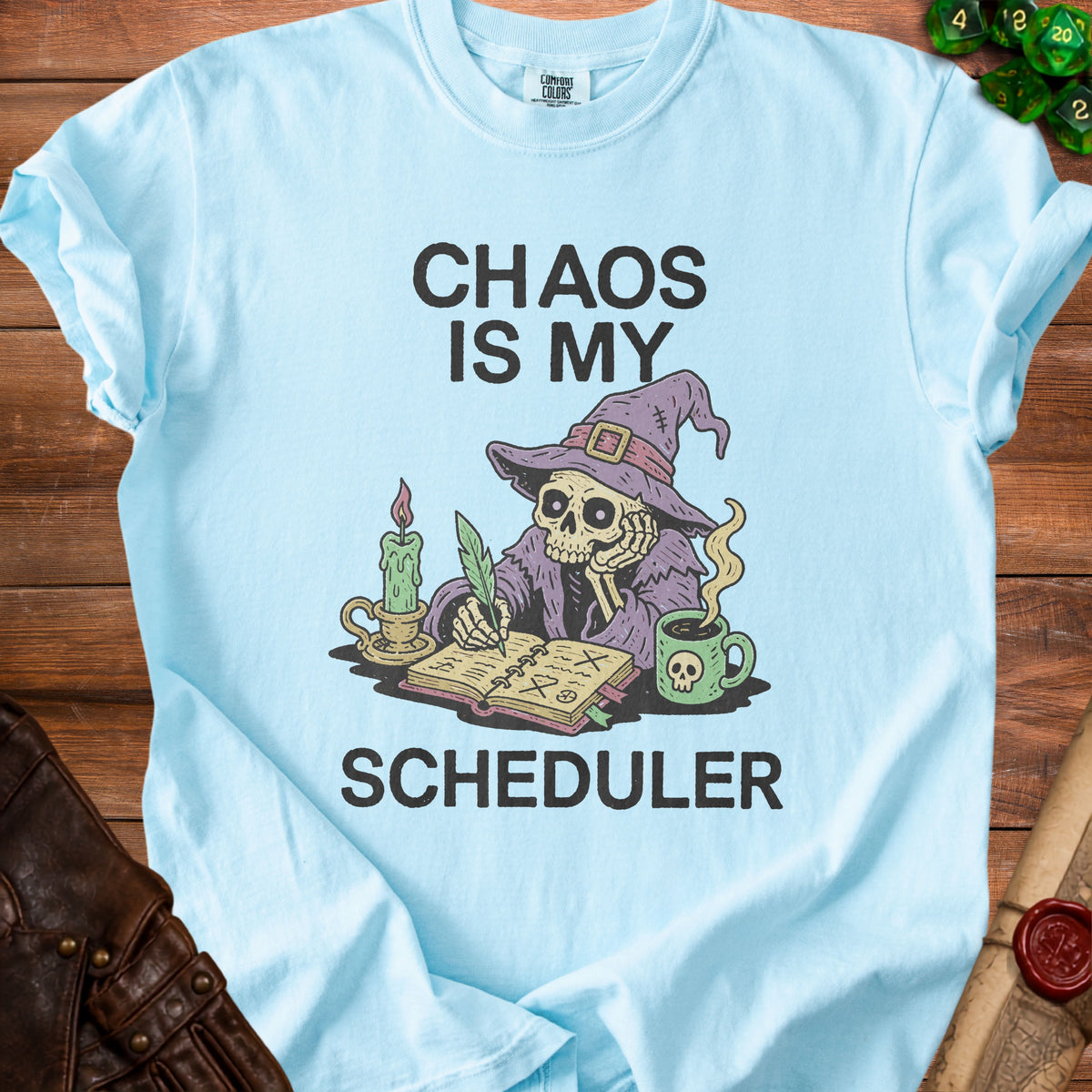 Light blue t-shirt with "CHAOS IS MY SCHEDULER" and skeleton drawing.