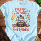 Light blue t-shirt with a cat in a witch hat, cauldron, and text.