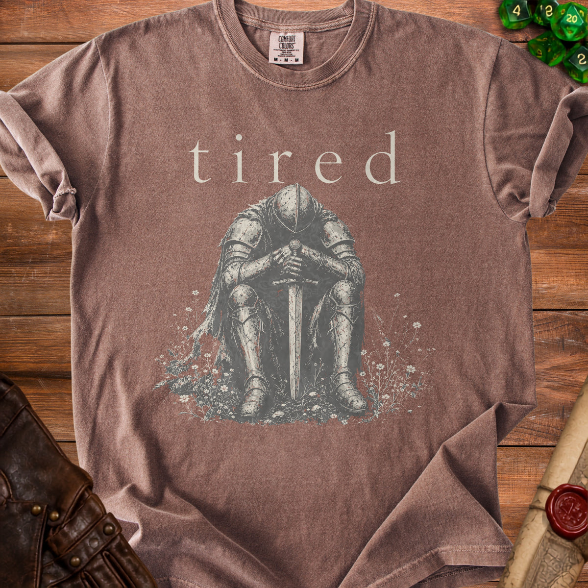 Brown t-shirt with knight and the word "tired" printed on it.