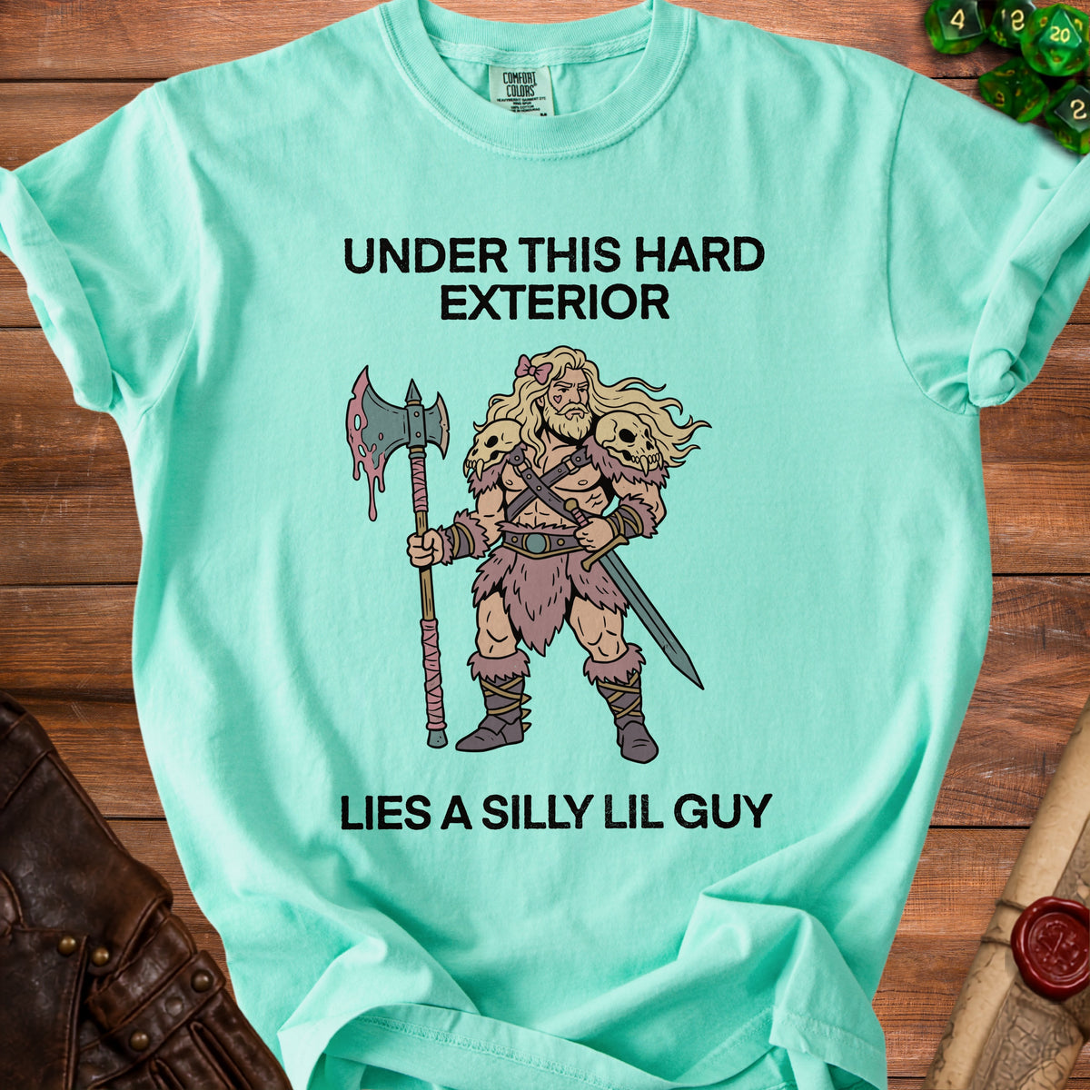 Teal t-shirt with text "Under this hard exterior lies a silly lil guy" and barbarian illustration.