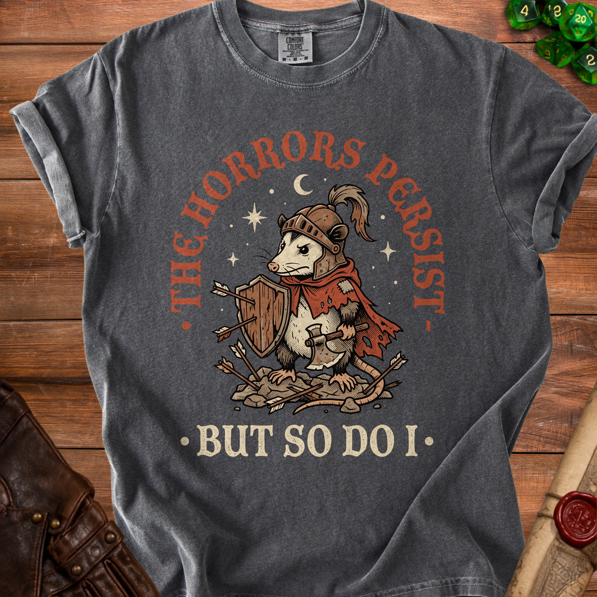 Graphic tee with a knight opossum holding a shield and axe, text reads "THE HORRORS PERSIST BUT SO DO I".