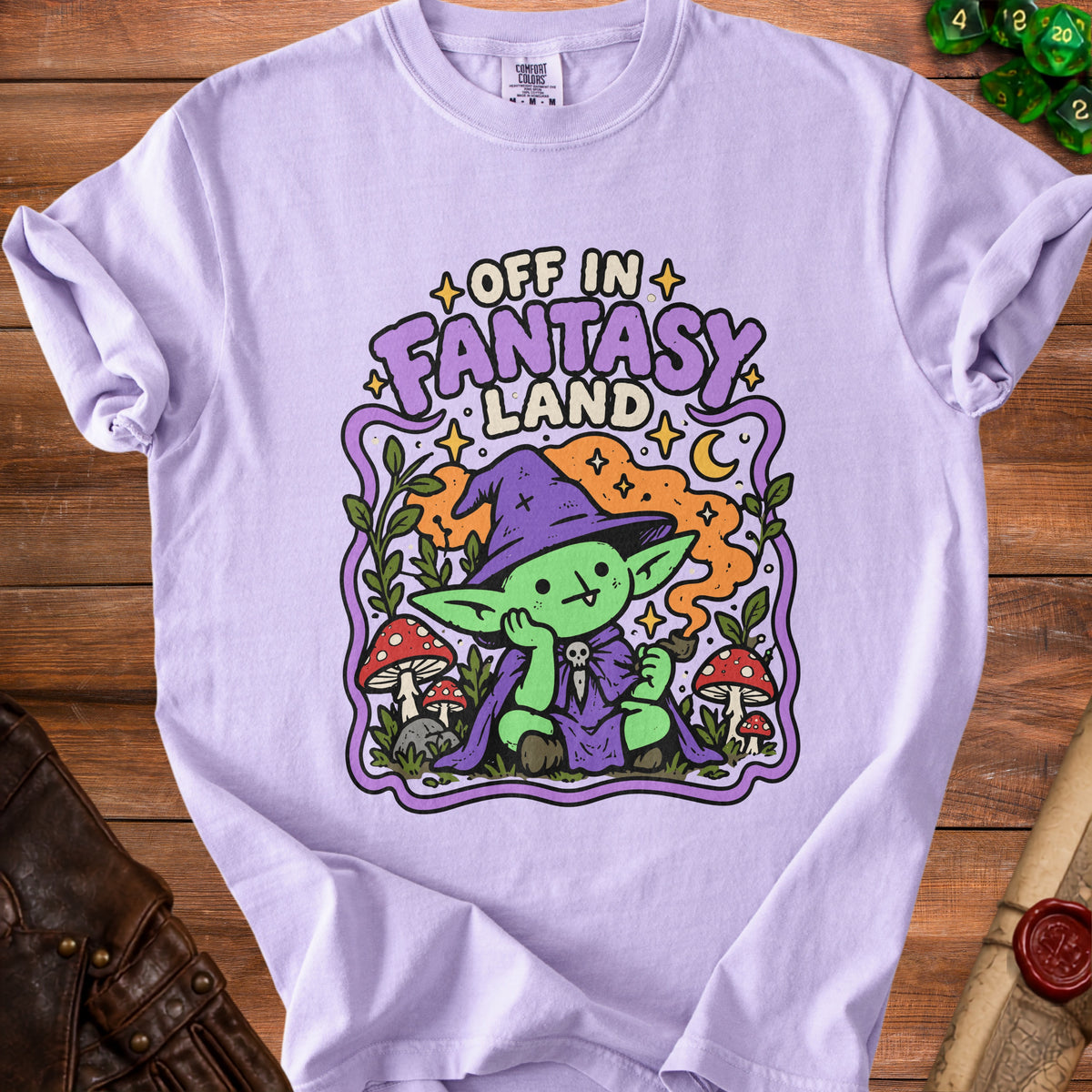 Lavender t-shirt with "Off in Fantasy Land" text and cartoon goblin graphic.